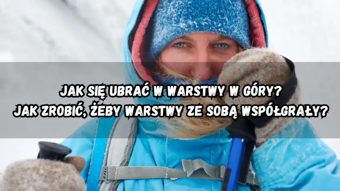 Kobieta w zimowej kurtce i czapce, z niebieskimi oczami, przygotowuje się do wędrówki. Dowiedz się, jak ubrać się w góry warstwowo.