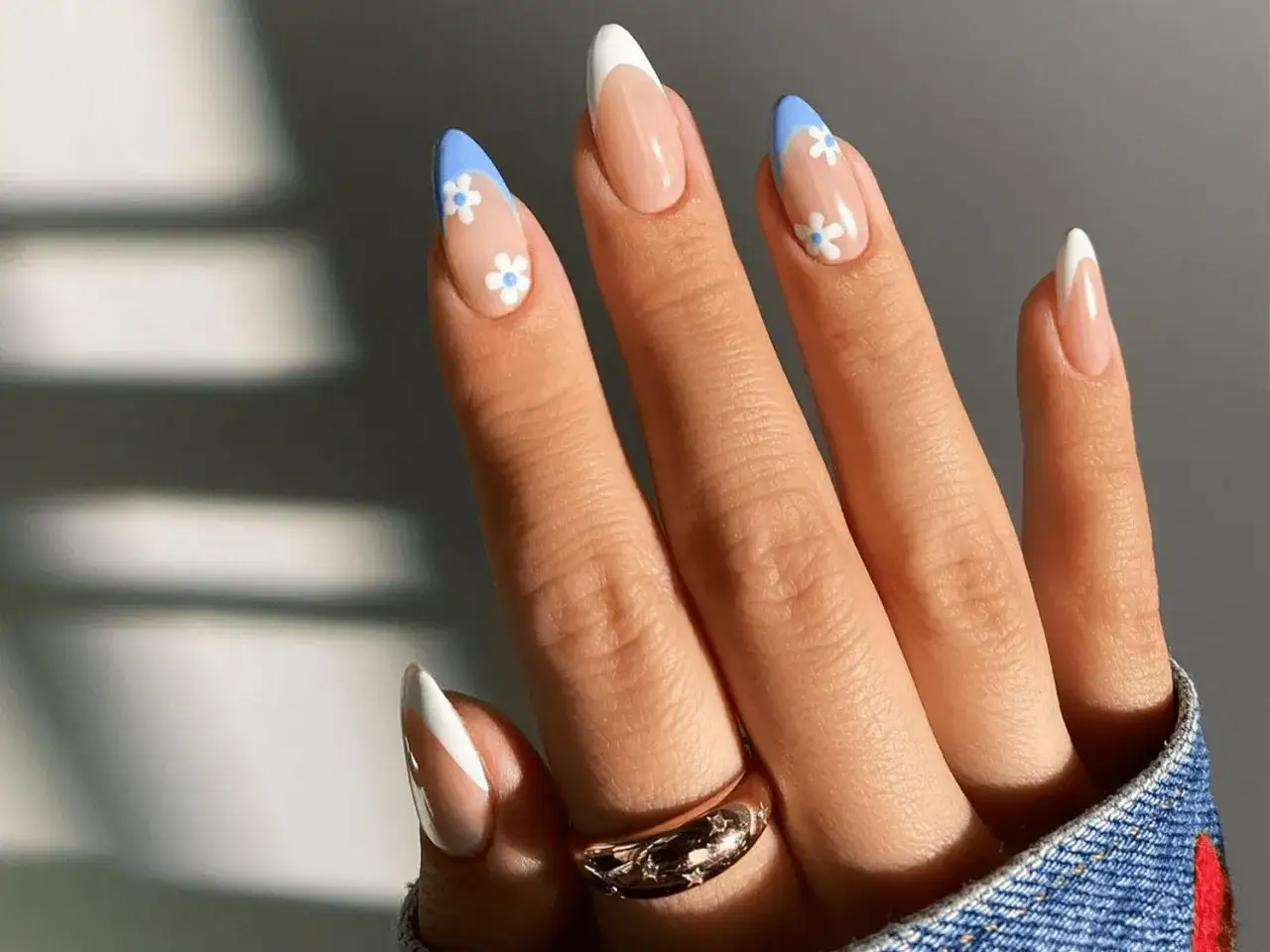 Elegancki french manicure z błękitnymi końcówkami i uroczymi białymi kwiatkami.