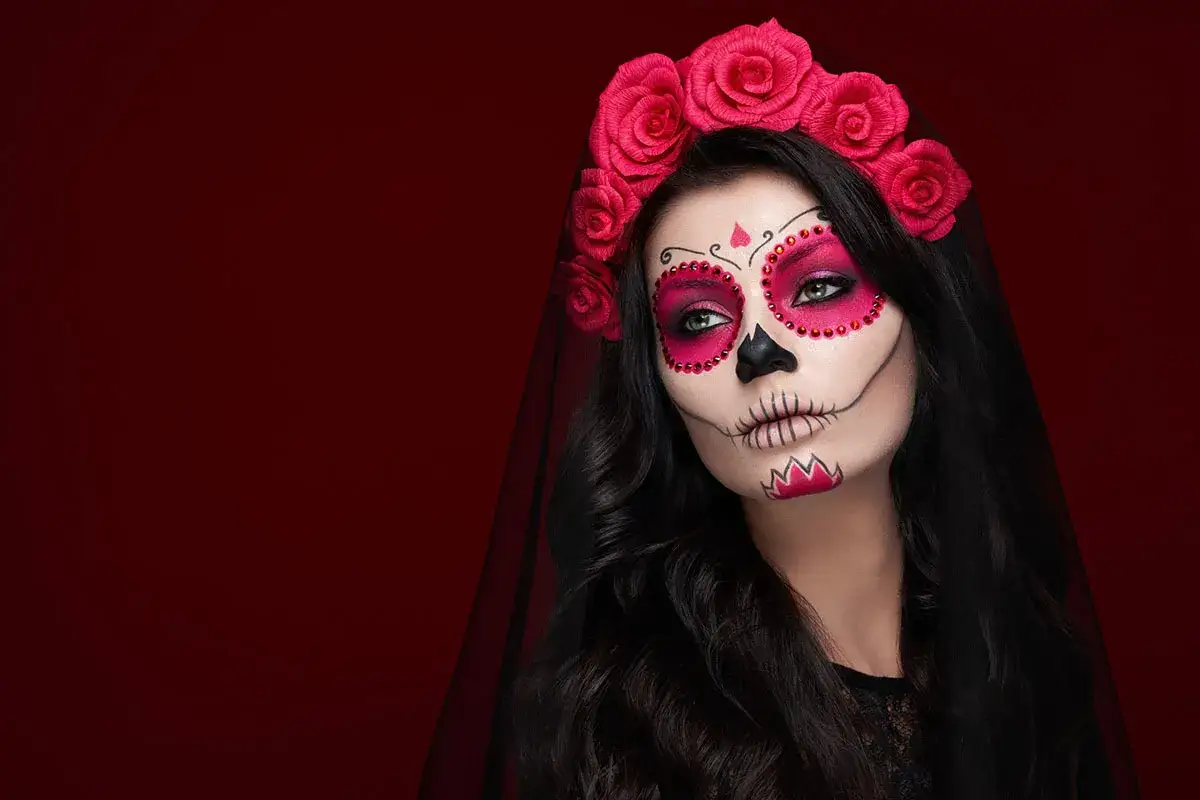 Kobieta z delikatnym makijażem na Halloween w stylu Catriny. Różana opaska i czarna woalka dodają tajemniczości.