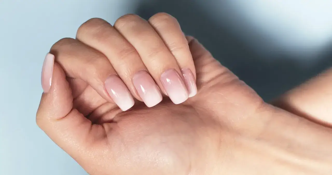 Dłoń z paznokciami w stylu baby boomer – delikatny gradient od różu do bieli, subtelny i elegancki.