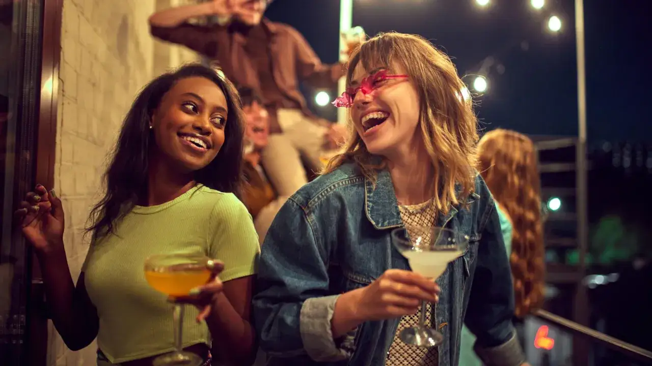 Uśmiechnięte kobiety z drinkami, idealna stylizacja na wyjście z koleżankami.