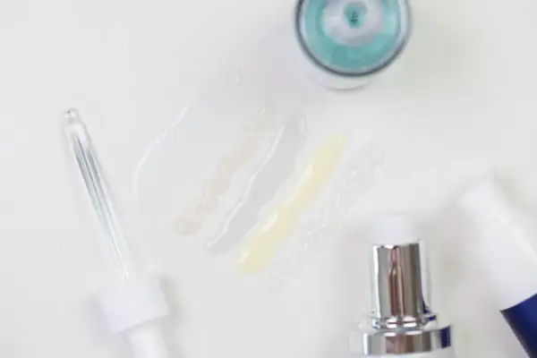 Delikatne kosmetyki z kwasem laktobionowym w ciąży. Próbki serum i kremów, pipeta i pompki dozujące.
