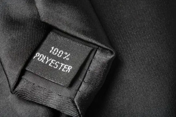 Czarna metka na krawacie informuje: 100% poliester. To materiał, z którego jest wykonany.
