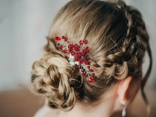 Eleganckie fryzury komunijne z warkoczem i ozdobą z czerwonych koralików. Delikatny warkocz oplata głowę, tworząc romantyczną całość.