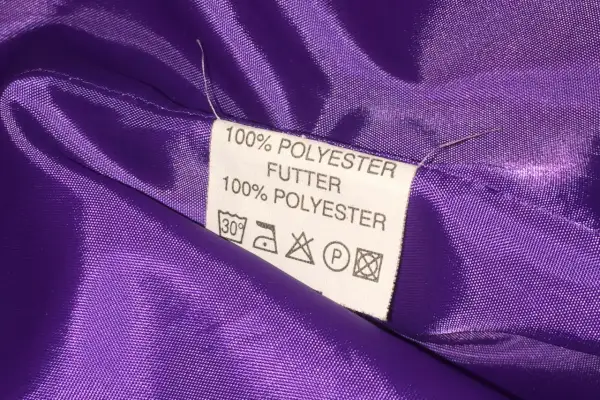 Metka z napisem "100% POLYESTER FUTTER" na fioletowej, błyszczącej podszewce. Czy poliester jest zdrowy? Pytanie pozostaje otwarte.