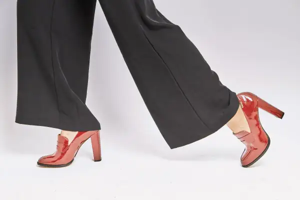 Czerwone lakierowane mokasyny na słupku idealnie pasują do szerokich, czarnych, eleganckich spodni.