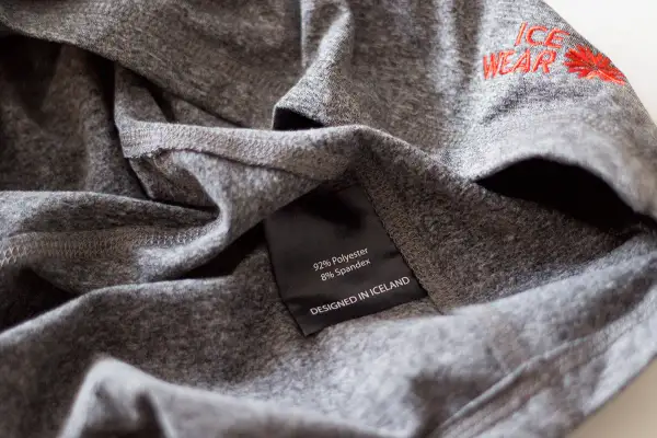 Szara koszulka z metką "92% Polyester 8% Spandex". Czy poliester się gniecie? Ta tkanina wygląda na odporną na zagniecenia.