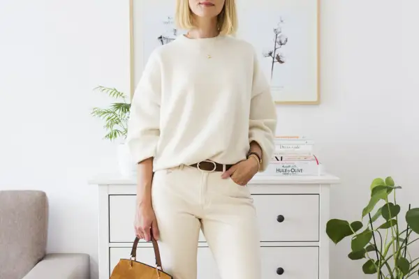 Eleganckie biały sweter stylizacje: luźny sweter, beżowe spodnie, brązowy pasek i torebka.