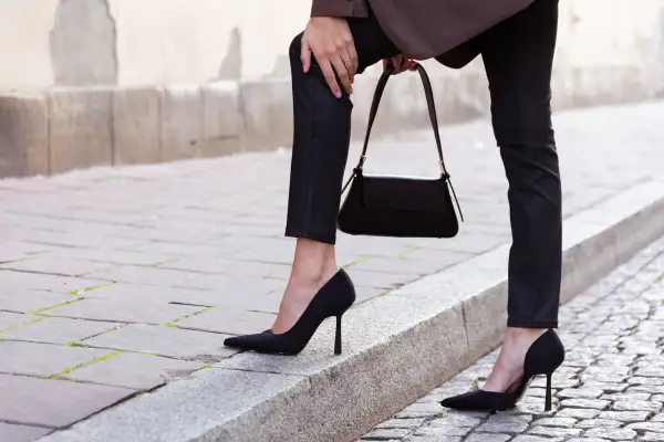 Eleganckie czarne szpilki to idealne buty do wąskich spodni damskich. Stylizacja uzupełniona o czarną torebkę.